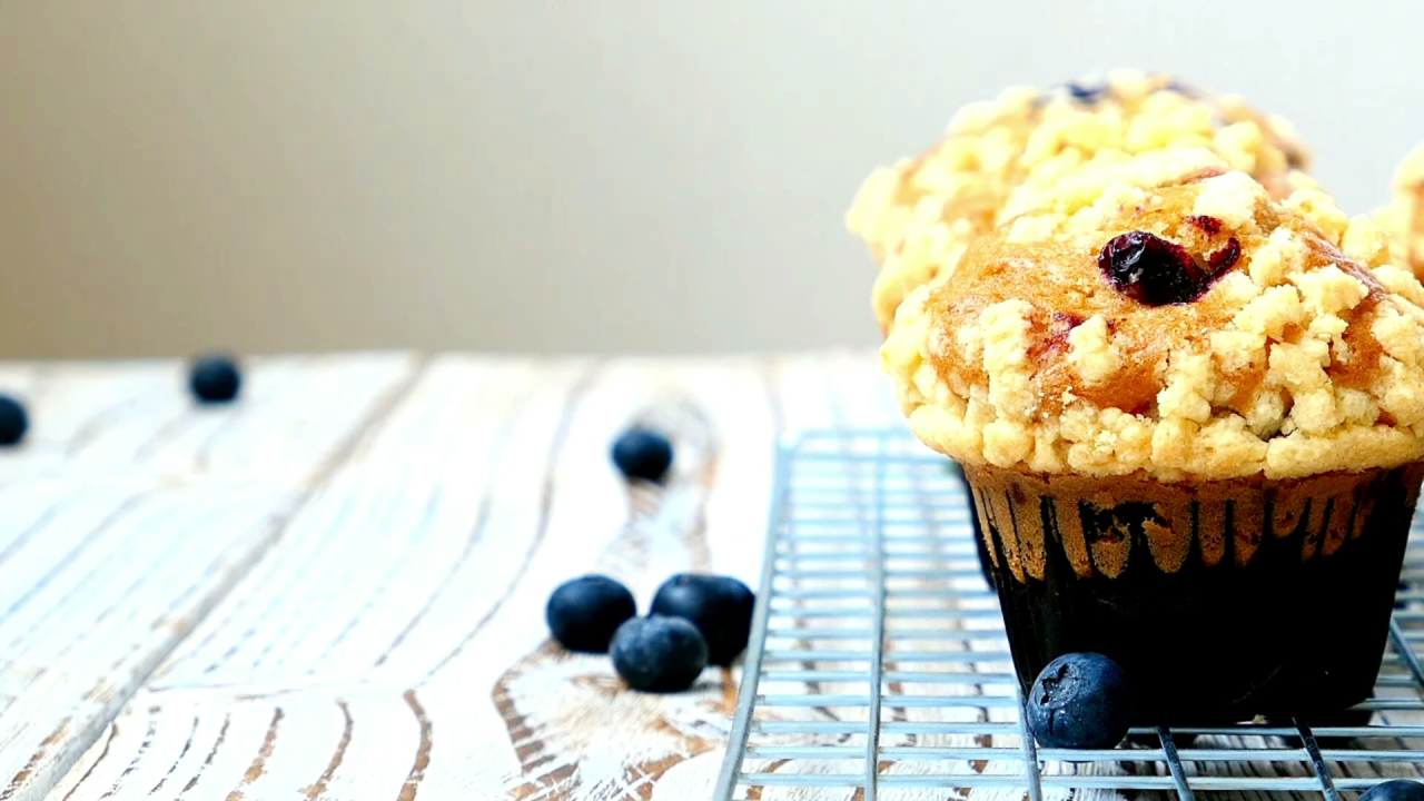 A golden-topped blueberry crumble muffin with visible blueberries and crumble topping